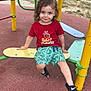 black_sandals, child, cute, dinosaur_prints, green_shorts, happy, outdoor, park, person, play_equipment, playground, recreation, red_tshirt, sand, skateboard, smiling, summer_clothing, toddler, trees, yellow