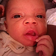 Vivian is registered to the contest to win money with this photo: baby, button, child, close_up, clothing, curious, cute, expression, eyes, face, hand, indoor, infant, mouth, newborn, person, portrait, skin, soft_light, young