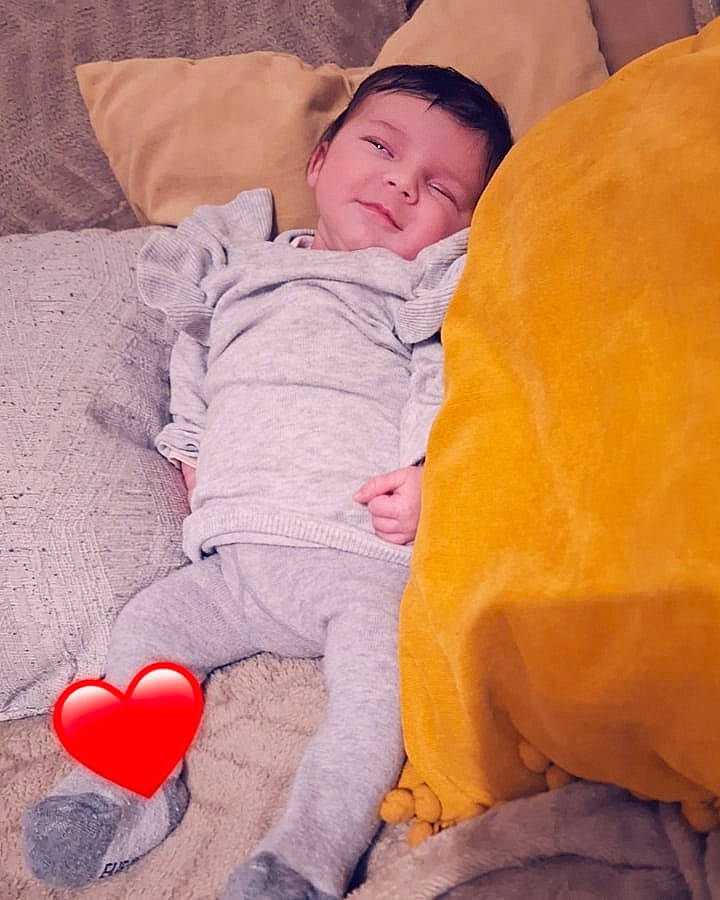 Lyana participe au concours pour gagner de l'argent avec cette photo : baby, baby_toddler_clothing, cheek, child, comfort, couch, facial_expression, flooring, happy, linens, mammal, nose, organ, person, photograph, pink, sitting, skin, smile, textile