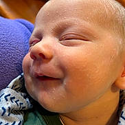 Oakley is registered to the contest to win money with this photo: baby, blanket, child, close_up, comfort, cozy, face, head, indoor, infant, newborn, patterned_blanket, peaceful, portrait, rest, skin, sleeping, smile, soft_texture, young