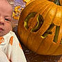 autumn, baby, carved_pumpkin, celebration, clothing, costume, cute, face, festive, food, guts, halloween, holiday, indoors, infant, orange, person, portrait, pumpkin, table