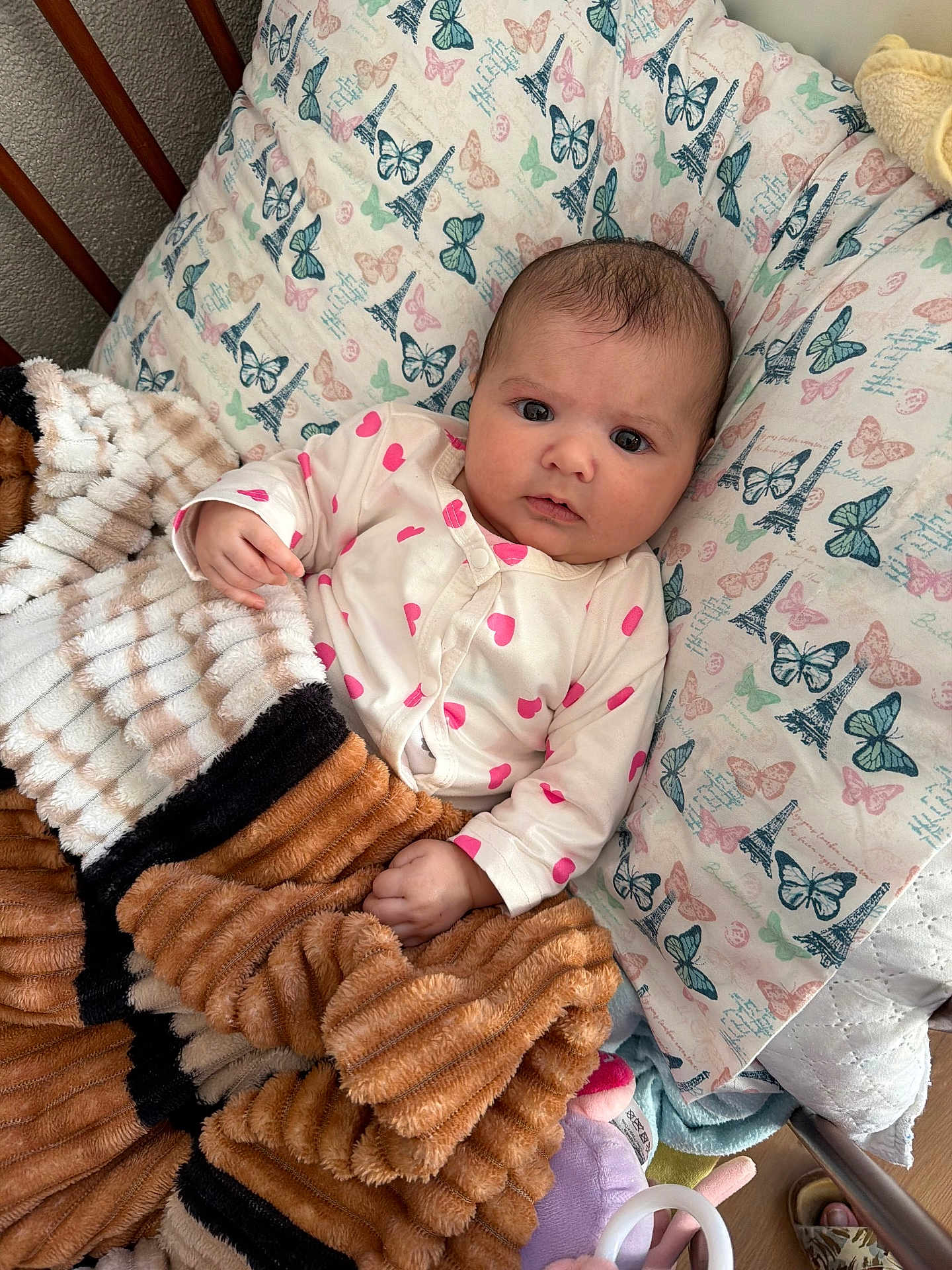 Linda a rejoint le concours — aidez-le/la à gagner de superbes lots ! baby, blanket, pillow, onesie, heart_pattern, butterfly_pattern, eiffel_tower_pattern, infant, bed, wooden_rail, cozy, soft_texture, indoor, child, cute, looking, lying_down, hand, face, expression