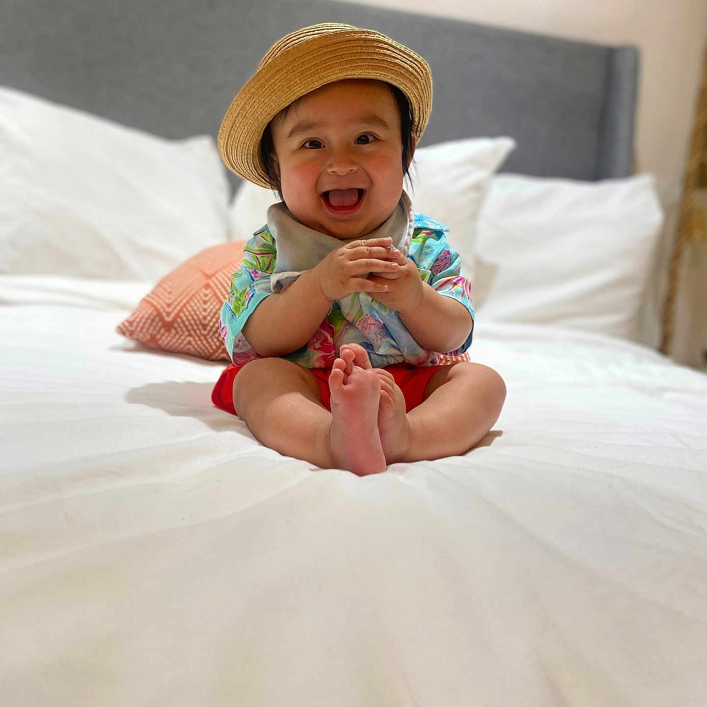 Emiliano is registered to the contest to win money with this photo: baby, bed, cheerful, child, clothing, colorful, cute, face, happy, hat, headwear, home, indoors, infant, person, pillow, portrait, sitting, smiling, young