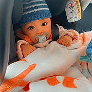 Maylana Pfeiffer a rejoint le concours — aidez-le/la à gagner de superbes lots ! baby, child, car_seat, pacifier, blanket, hat, knit_hat, striped_hat, orange, white, safety, infant, cute, warm, cozy, indoor, closeup, face, hands, seatbelt
