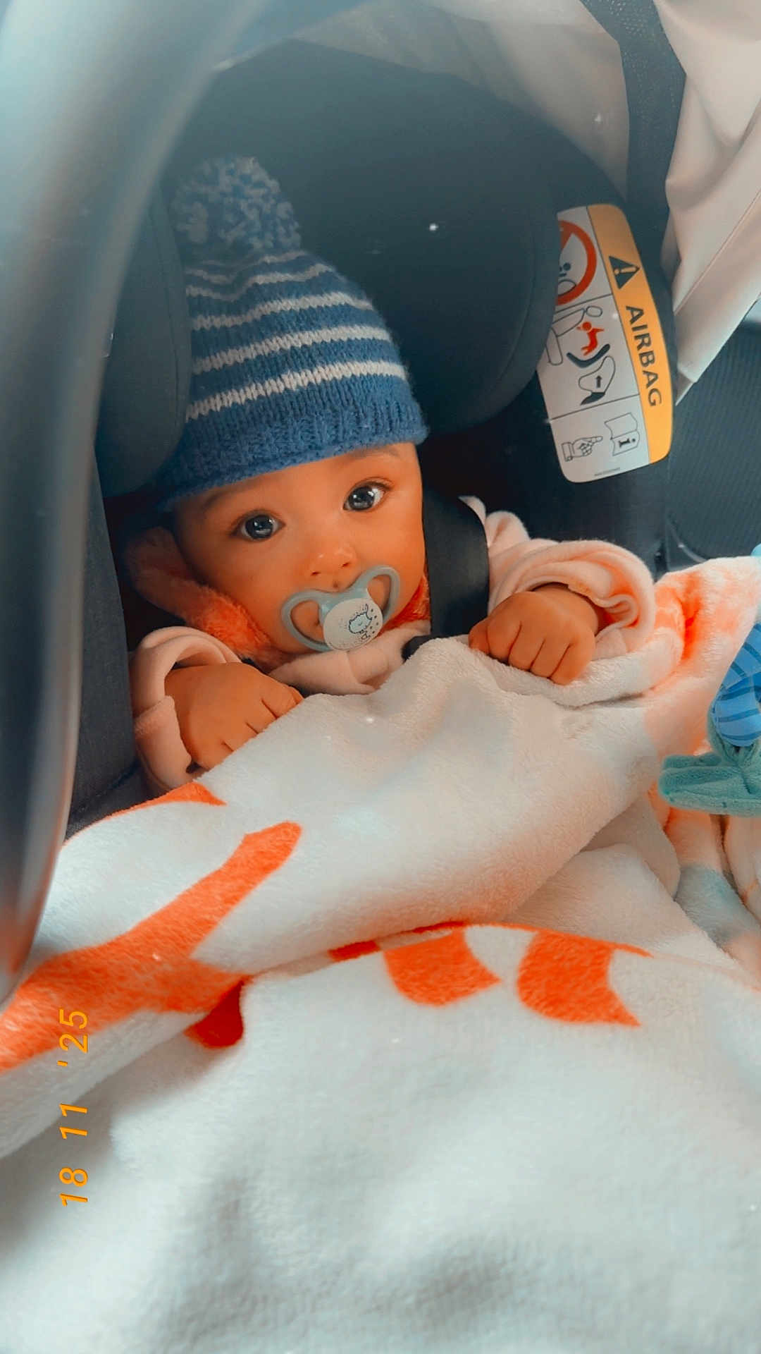 Maylana Pfeiffer a rejoint le concours — aidez-le/la à gagner de superbes lots ! baby, child, car_seat, pacifier, blanket, hat, knit_hat, striped_hat, orange, white, safety, infant, cute, warm, cozy, indoor, closeup, face, hands, seatbelt