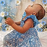 baby, child, blue_dress, floral_pattern, flowers, background, portrait, side_view, cute, adorable, soft_lighting, decor, earrings, sitting, indoor, infant, young_child, delicate, smiling, baby_girl