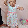 toddler, child, baby, standing, holding_hand, dress, mermaid_pattern, footwear, adult_hand, plush_toy, indoor, white_background, cute, early_walking, person, fabric, soft_toys, colorful, smiling, portrait