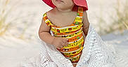 Isabella is registered to the contest to win money with this photo: baby, child, hat, pink_hat, blanket, beach, ocean, sand, portrait, cute, outdoor, sunhat, lacy_blanket, infant, summer, clothing, person, young_child, sitting, nature