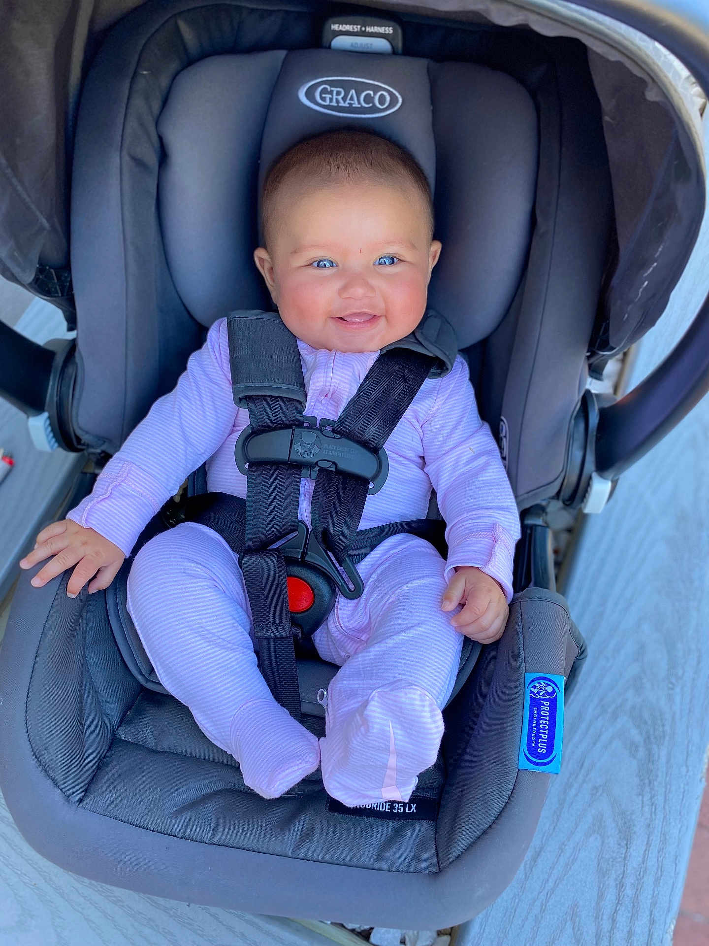 Zanaiah is registered to the contest to win money with this photo: baby, infant, car_seat, graco, child, smiling, blue_eyes, pink_onesie, seatbelt, safety_harness, cute, happy, strapped_in, indoor, person, small_hands, footed_pajamas, headrest, baby_gear, child_safety