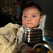 Abbas is registered to the contest to win money with this photo: baby, child, infant, bib, toy, hand, face, eyes, clothing, blanket, indoor, soft_light, curious, play, person, portrait, cute, young_child, warm_light, striped