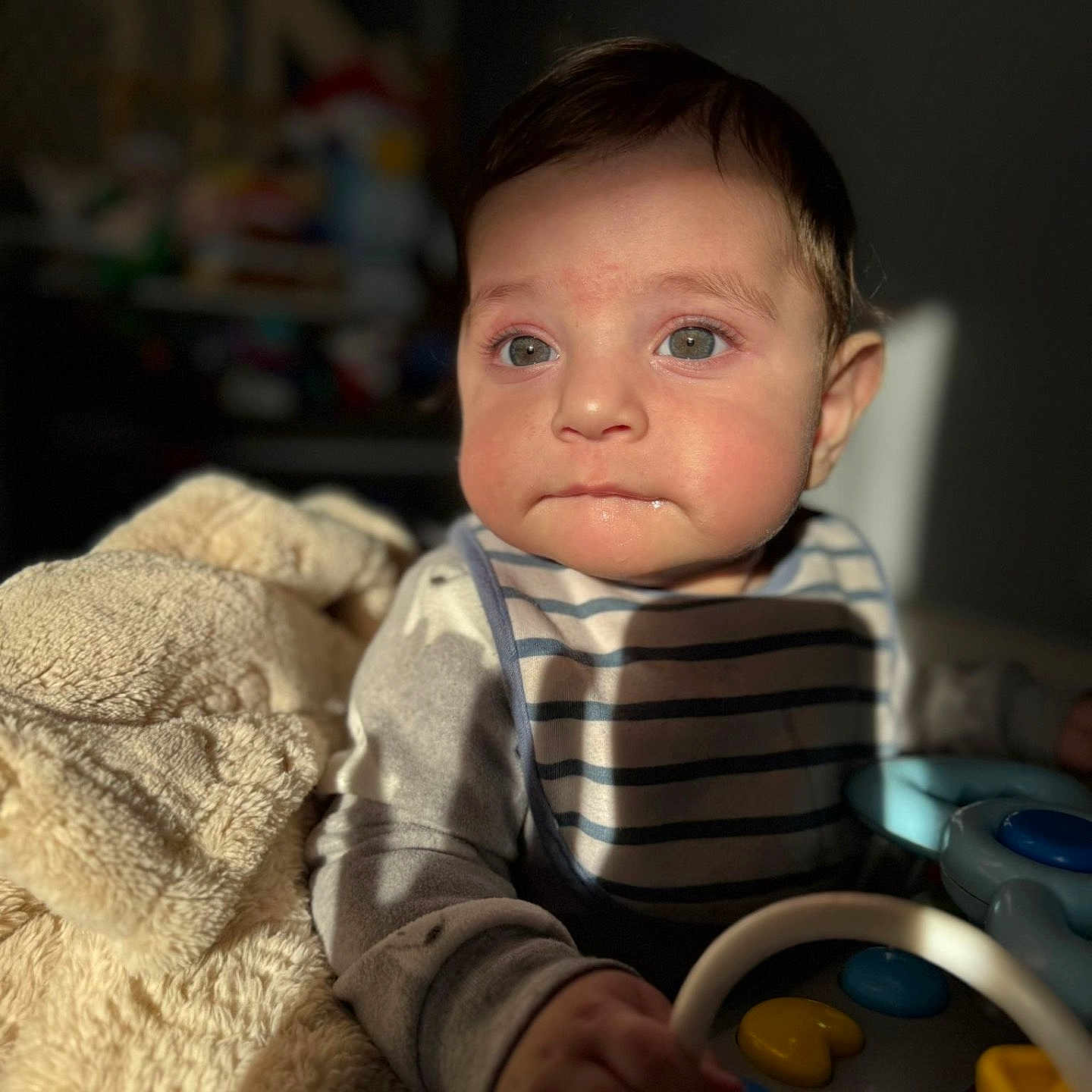Abbas is registered to the contest to win money with this photo: baby, bib, blanket, child, clothing, curious, cute, eyes, face, hand, indoor, infant, person, play, portrait, soft_light, striped, toy, warm_light, young_child