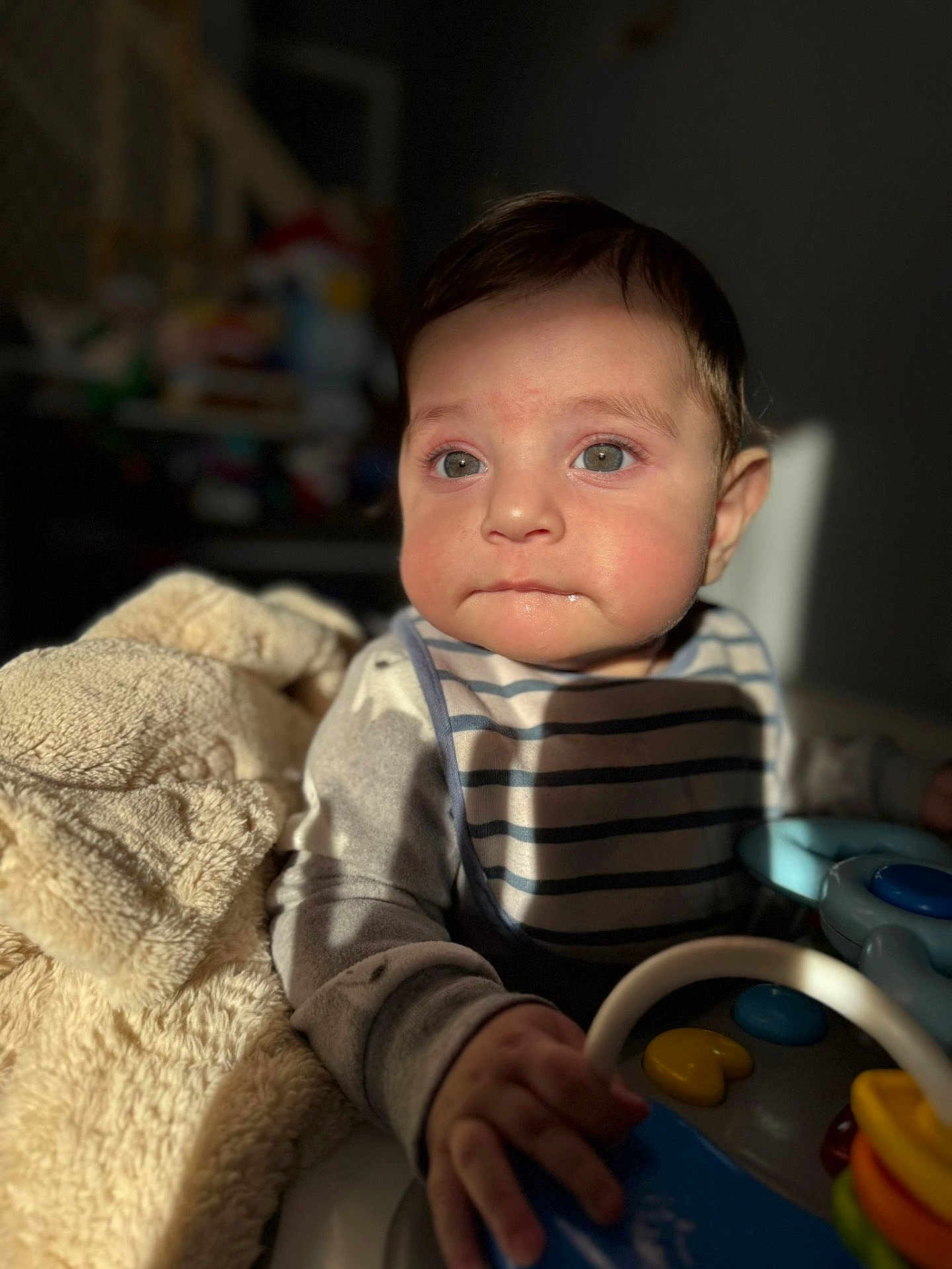Abbas is registered to the contest to win money with this photo: baby, child, infant, bib, toy, hand, face, eyes, clothing, blanket, indoor, soft_light, curious, play, person, portrait, cute, young_child, warm_light, striped