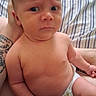 Sammuel joined the competition — help win amazing prizes! baby, infant, child, portrait, sitting, diaper, bare_chested, wide_eyed, serious_expression, indoor, bed, striped_bedding, adult_arm, family_photo, closeup, skin, head, face, photograph, phone_interface