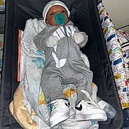Jermaine joined the competition — help win amazing prizes! baby, baby_seat, blanket, child, clothing, comfort, cute, footwear, hat, indoors, infant, nike, onesie, pacifier, portrait, resting, sneakers, soft, wearing, young