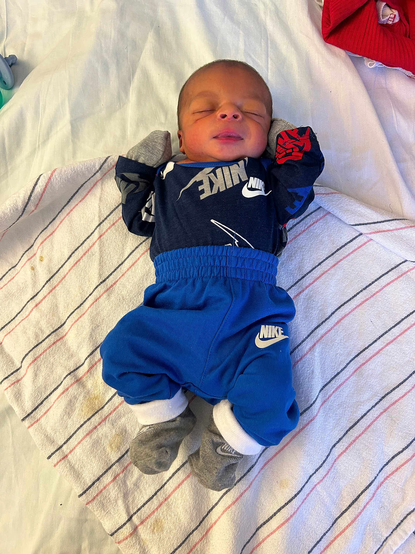 Jermaine joined the competition — help win amazing prizes! newborn, baby, sleeping, clothing, nike, towel, striped_towel, sock, mittens, infant, person, bed, resting, cute, small, peaceful, indoor, laying, apparel, child