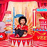 Veer joined the competition — help win amazing prizes! toddler, child, circus, carnival, costume, red_curtains, popcorn, camera, drum, signpost, studio, platform, hat, smiling, colorful, indoor, props, festive, portrait, playful