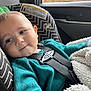 baby, child, car_seat, seatbelt, teal_clothing, blanket, car_interior, window, autumn, fall_colors, smile, face, head, person, young_child, safety, cute, indoor, soft_texture, cozy