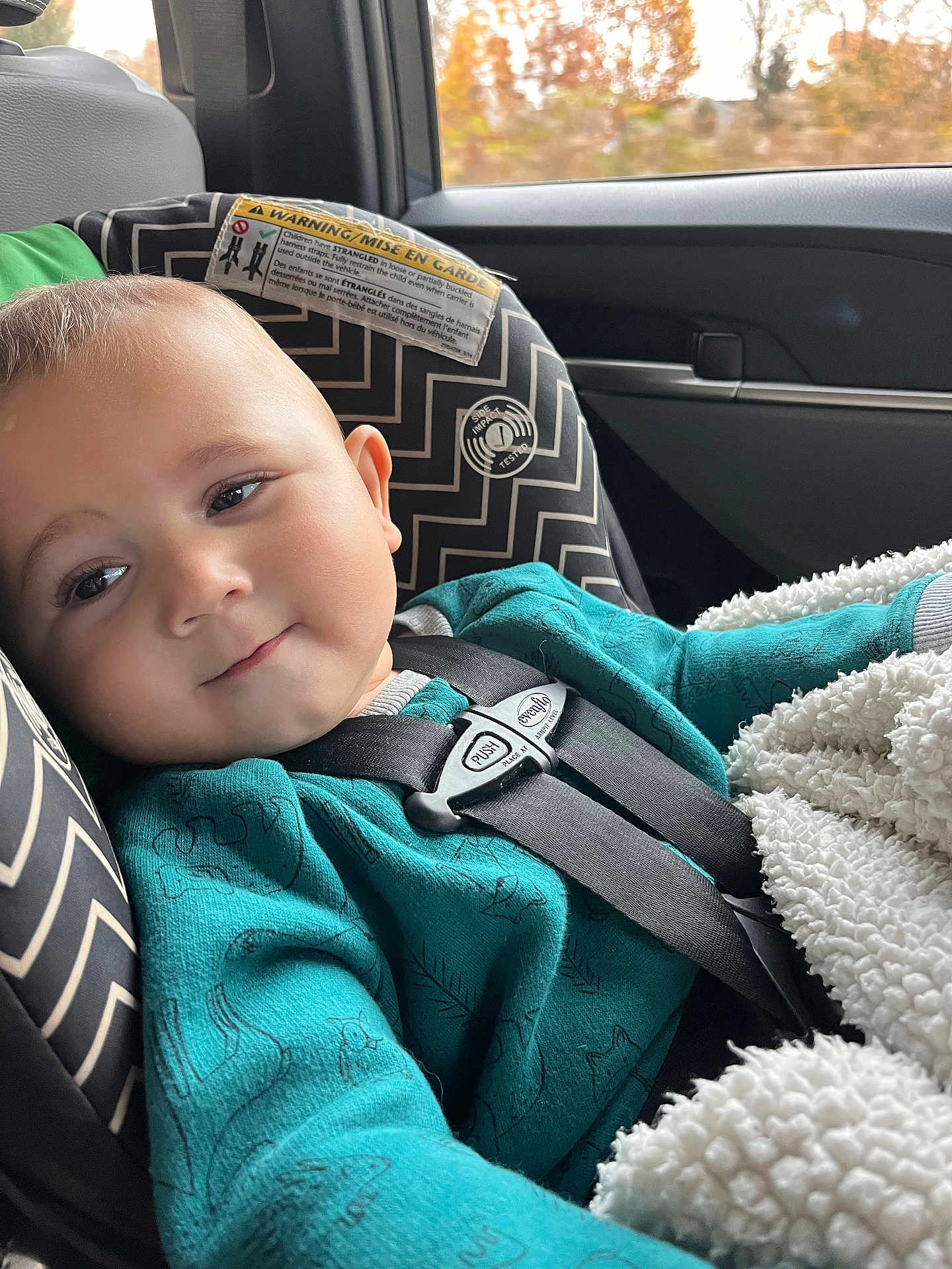 James joined the competition — help win amazing prizes! baby, child, car_seat, seatbelt, teal_clothing, blanket, car_interior, window, autumn, fall_colors, smile, face, head, person, young_child, safety, cute, indoor, soft_texture, cozy