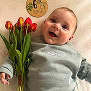 Andrea participe au concours pour gagner de l'argent avec cette photo : baby, tulips, flowers, milestone, 6_months, plaque, adidas, clothing, smiling, face, infant, cute, portrait, happy, green_leaves, indoor, soft_surface, person, child, celebration