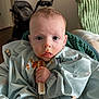 baby, messy_face, bib, teething_toy, food_stains, blue_clothing, indoor, blanket, stroller, curious_eyes, child, sitting, infant, hand, mouth, face, person, portrait, young_child, home