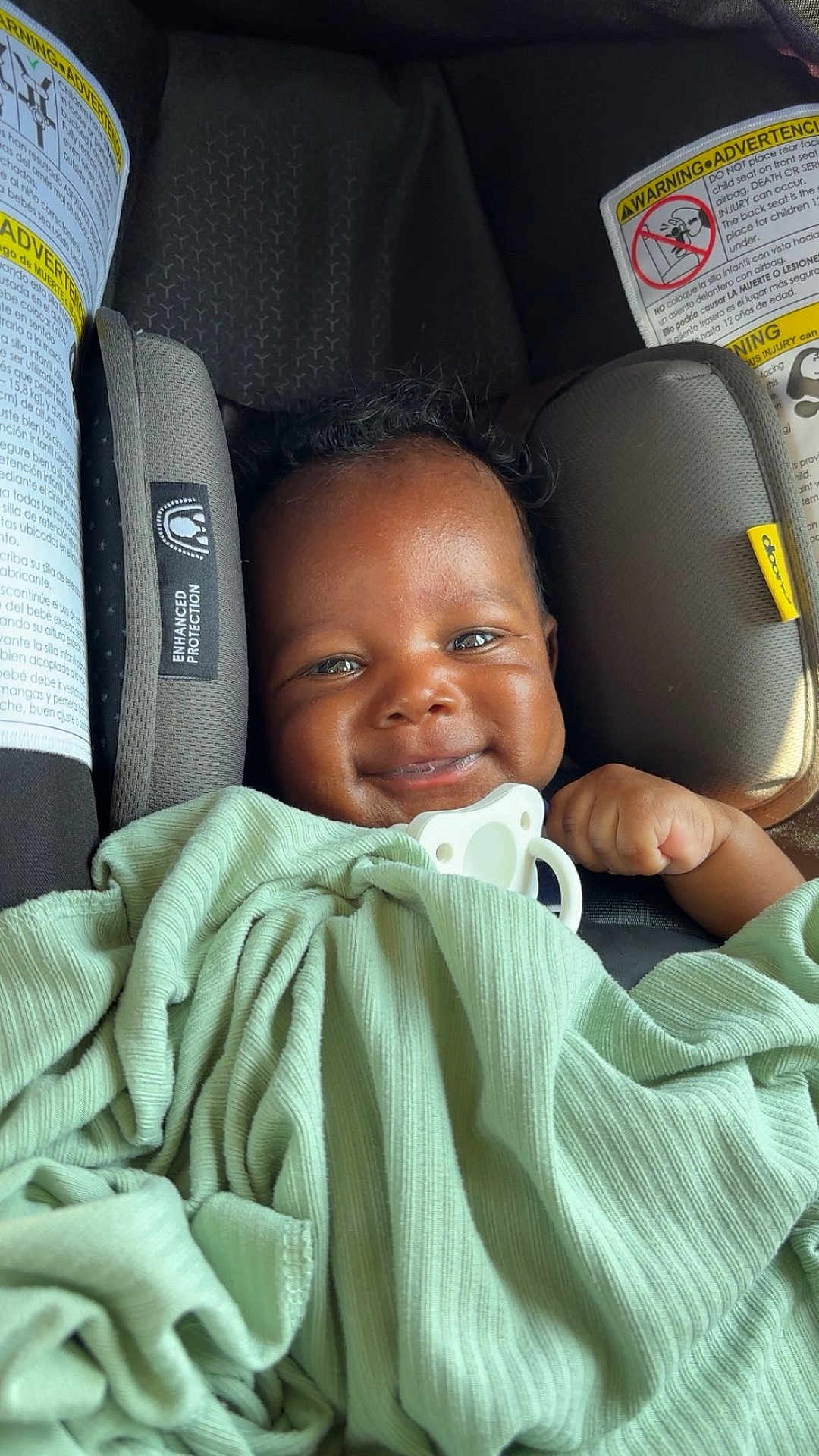 Wesley joined the competition — help win amazing prizes! baby, smile, blanket, car_seat, child, face, infant, cute, happy, indoors, protection, warning_label, pacifier, wrapped, clothing, seat_belt, safety, person, portrait, young