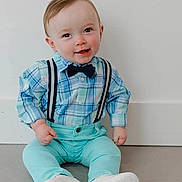 Kayn is registered to the contest to win money with this photo: baby, blue_clothing, bow_tie, boy, casual, child, cute, fashion, floor, happy, indoor, infant, person, plaid_shirt, portrait, sitting, smiling, suspenders, white_wall, young