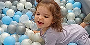 Théa participe au concours pour gagner de l'argent avec cette photo : ball_pit, blue_balls, child, colorful, curly_hair, cushion, fun, happy, indoor, padded_edges, play, playroom, purple_clothing, scrunchie, silver_balls, smiling, soft_furniture, toddler, toy, white_balls
