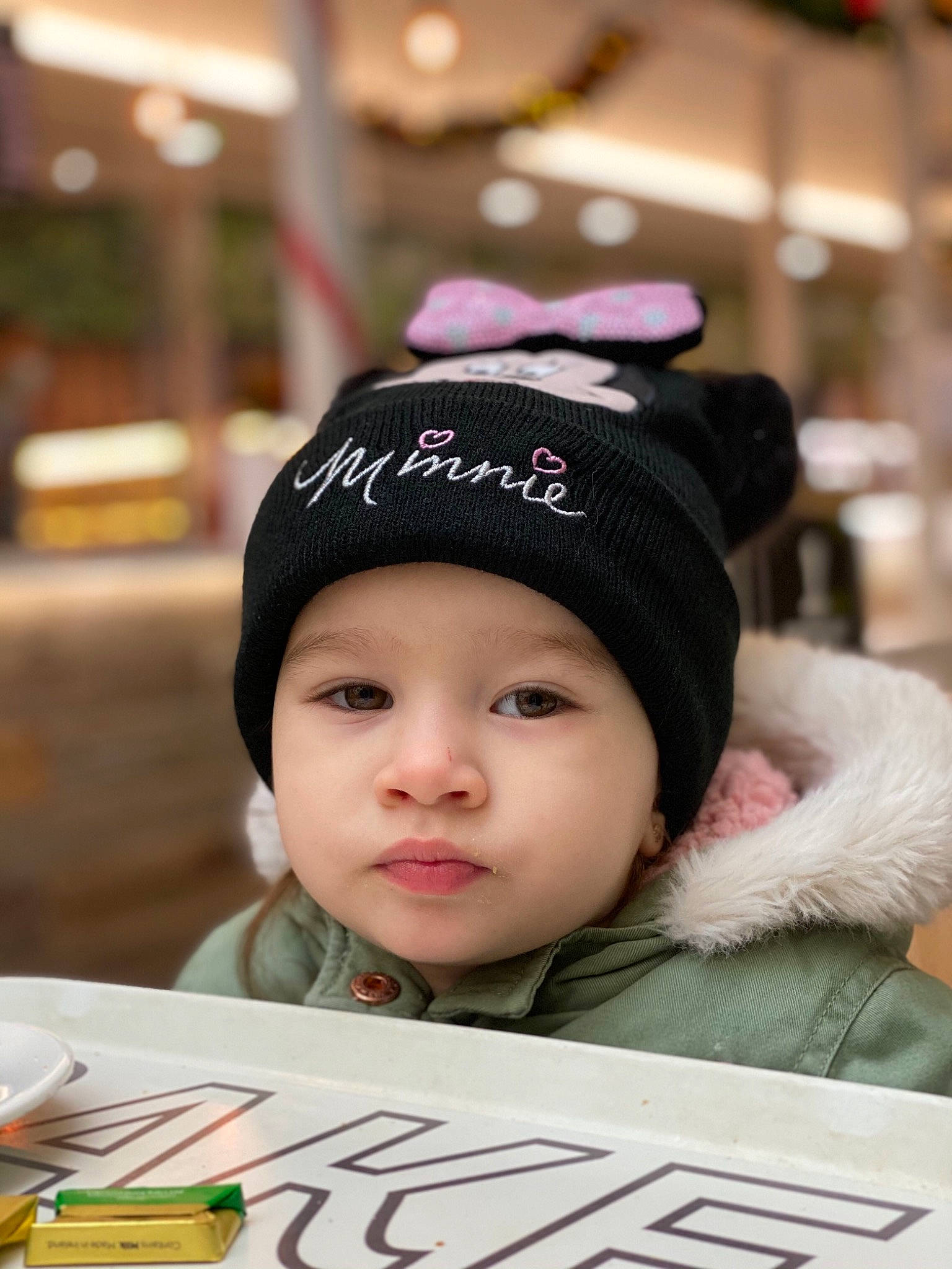 Irene is registered to the contest to win money with this photo: beanie, black_hair, cap, cheek, child, eyebrow, eyelash, fashion_accessory, fun, happy, headgear, headwear, knit_cap, person, portrait_photography, room, skin, street_fashion, table, toddler