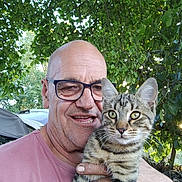 Tom a rejoint le concours — aidez-le/la à gagner de superbes lots ! man, glasses, bald, smiling, holding, cat, tabby_cat, kitten, outdoor, tree, greenery, leaf, nature, car, shirt, portrait, happy, pet, animal, person