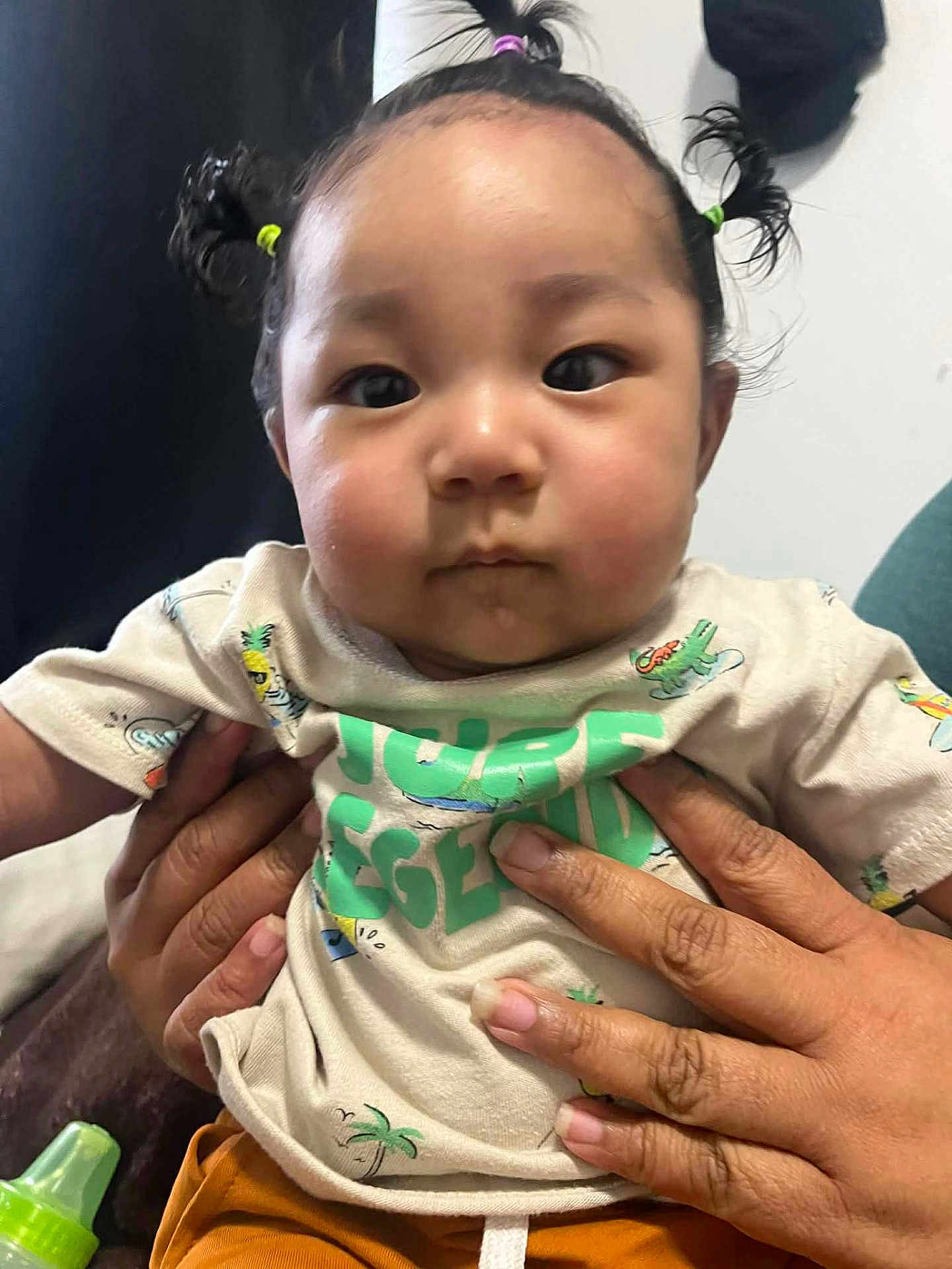 Mercellus Hendson joined the competition — help win amazing prizes! baby, child, hands, person, toddler, shirt, orange_pants, ponytails, face, cute, indoor, expression, holding, clothing, skin, fingers, infant, young_child, casual, portrait