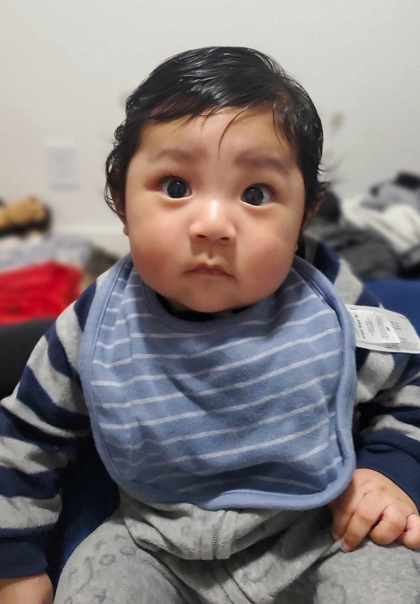 Mercellus Hendson joined the competition — help win amazing prizes! baby, bib, blurry_background, child, curly_hair, cute, expression, face, focus, gray_pants, hand, indoor, infant, navy_sweater, portrait, sitting, soft_lighting, striped_clothing, wide_eyes, young_child