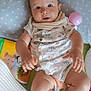 baby, blanket, blue_eyes, book, child, clothing, curious, cute, diaper, face, foot, hand, indoor, infant, lying_down, pillow, polka_dot, skin, soft_toys, toy