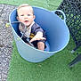 Loé a rejoint le concours — aidez-le/la à gagner de superbes lots ! artificial_grass, baby, bandana, blue_bucket, bucket, child, clothing, curious, daylight, exploration, face, green, infant, outdoor, person, playful, reaching_hand, seat, texture, wicker_chair
