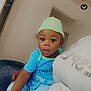 Jahsir is registered to the contest to win money with this photo: baby, blue_clothing, child, curious, doorway, eyes, face, green_hat, hand, hat, headwear, indoor, lap, pajamas, person, room, sitting, skin, toddler, young