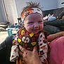 baby, infant, smiling, headband, turkey_patch, turkey_costume, autumn_print, living_room, couch, adult_hand, holding, hair_spikes, door, toy_table, pillow, blanket, festive, pumpkin, person, indoor