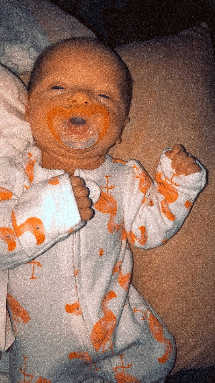Judith is registered to the contest to win money with this photo: arm, baby, baby_toddler_clothing, cheek, child, eye, finger, fun, gesture, happy, mouth, nose, orange, pattern, peach, person, personal_protective_equipment, skin, sleeve, thumb