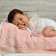 Anari is registered to the contest to win money with this photo: baby, infant, white_lace, pink_blanket, pearls, small_bed, curly_hair, cute, portrait, lying_down, soft_texture, cozy, indoor, wooden_bed, pale_skin, newborn, resting, decorative_blanket, toddler, sleepwear