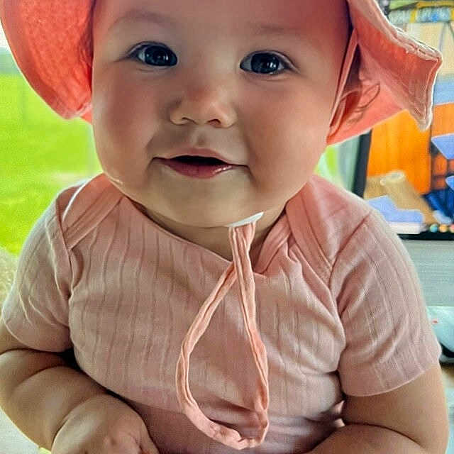 Katie is registered to the contest to win money with this photo: accessories, baby, baseballcap, bonnet, cap, clothing, dress, face, grass, happy, hat, head, jewelry, necklace, person, photography, plant, portrait, smile, sunhat