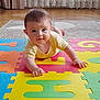 baby, child, colorful_mat, crawling, curtains, cute, eyes, face, floor, foam_puzzle, hand, home_interior, indoors, infant, lace_curtains, person, playtime, wooden_floor, yellow_clothing, young_child