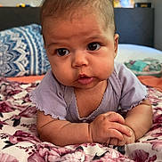 Violet joined the competition — help win amazing prizes! baby, infant, child, face, eyes, hands, blanket, floral, purple_clothing, bedroom, pillow, home_interior, curious, lying_down, portrait, skin, cute, young, indoors, soft_light
