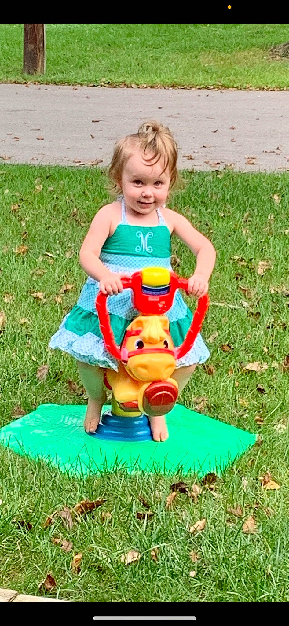 Maci is registered to the contest to win money with this photo: baby, baby_toddler_clothing, child, fun, grass, grassland, happy, human_body, lawn, leisure, outdoor_play_equipment, people_in_nature, person, plant, recreation, shorts, sitting, smile, t_shirt, toddler