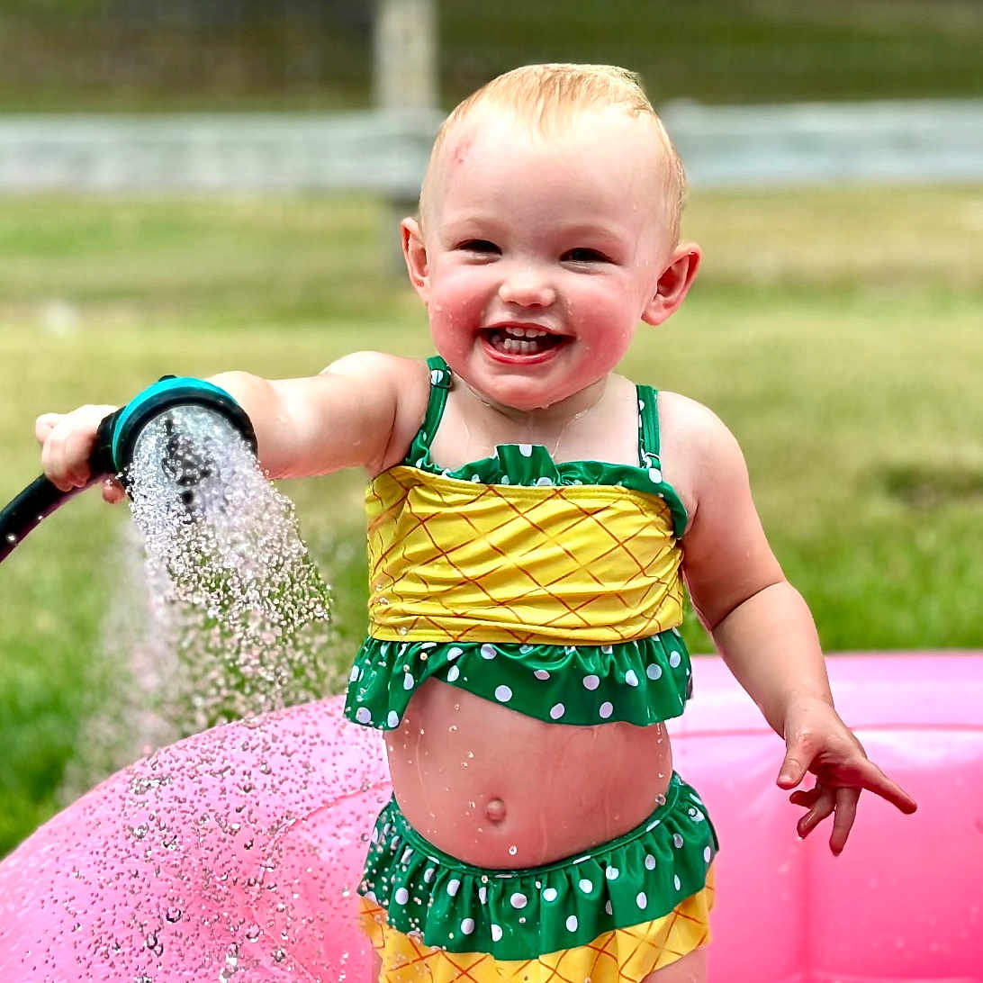 Mary-Alice joined the competition — help win amazing prizes! baby, child, cute, fence, fun, grass, happy, hose, inflatable_pool, outdoor, playtime, pool, smiling, splashing, summer, sunny, swimsuit, toddler, water, water_spray