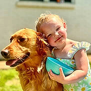 Mary-Alice joined the competition — help win amazing prizes! toddler, child, dog, golden_retriever, hug, smile, outdoor, sunlight, green_grass, blue_bowl, dress, flower_pattern, happy, pet, cute, summer, playful, closeup, portrait, friendship