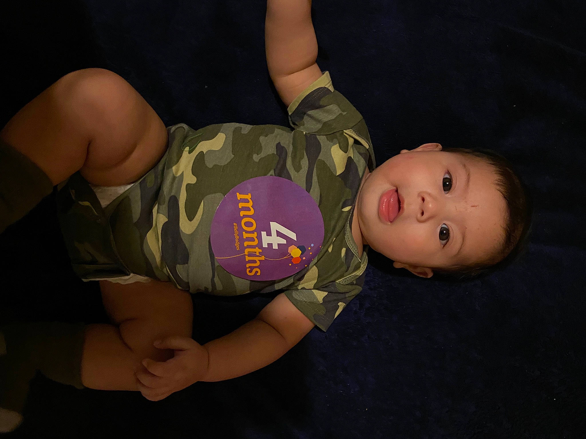 Jasiah is registered to the contest to win money with this photo: abdomen, baby, baby_products, baby_toddler_clothing, camouflage, chest, child, elbow, flash_photography, fun, gesture, human_leg, knee, military_camouflage, pattern, person, sitting, sleeve, thigh, toddler