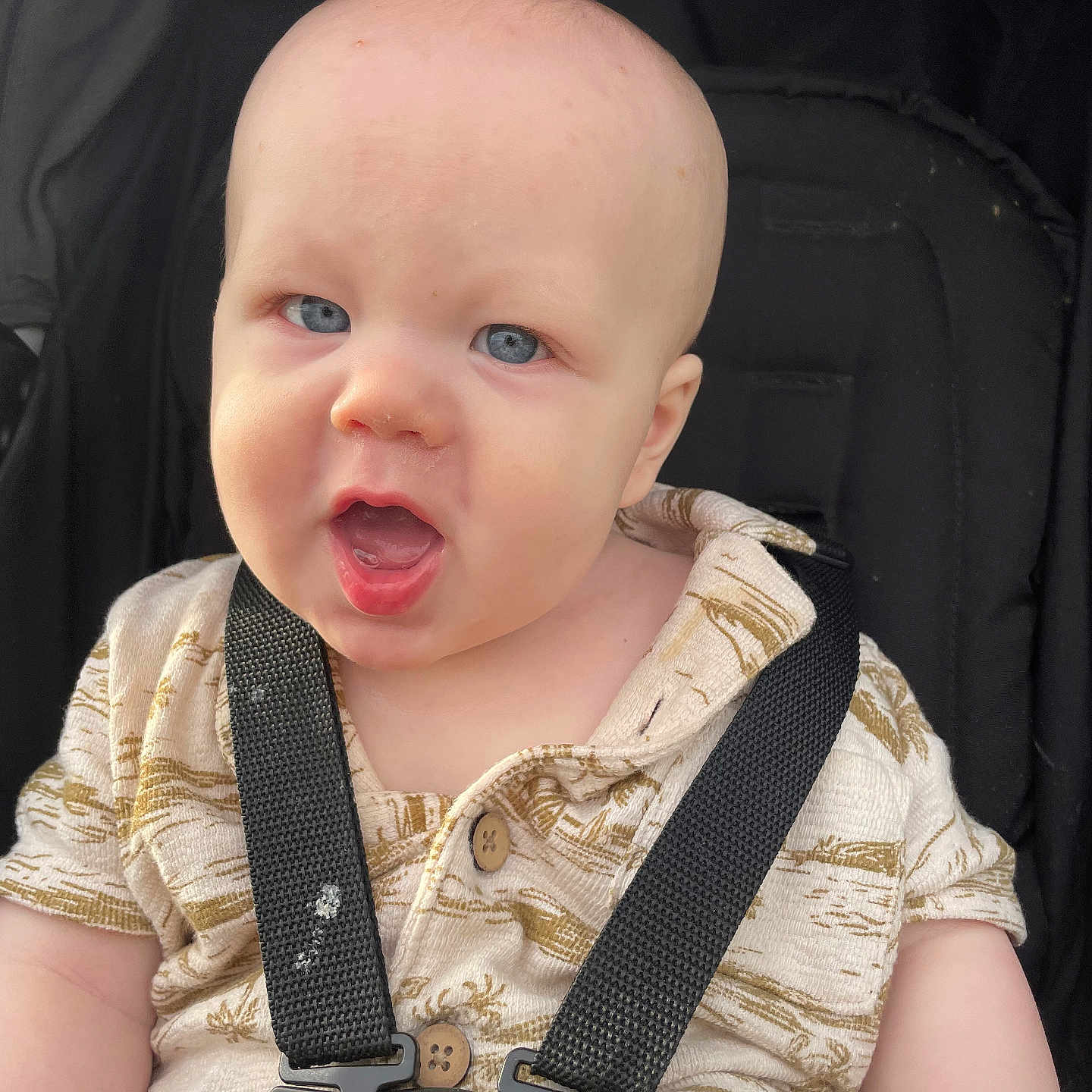 Daxter is registered to the contest to win money with this photo: baby, child, blue_eyes, harness, car_seat, shirt, infant, cute, expression, mouth_open, face, head, skin, person, safety, seat_belt, portrait, young, closeup, background