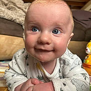 Arthur a rejoint le concours — aidez-le/la à gagner de superbes lots ! baby, infant, child, blue_eyes, drool, onesie, patterned_clothing, close_up, portrait, playmat, clasped_hands, smile, toy, couch, blanket, indoor, floor_mat, cheeks, expression, hand