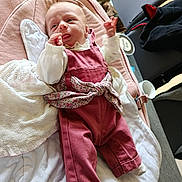 Ambre participe au concours pour gagner de l'argent avec cette photo : baby, baby_clothing, blanket, child, comfort, curious, cushion, cute, face, floral_bow, home, indoor, infant, lying_down, newborn, person, pink_overalls, small, soft_fabric, tongue_out