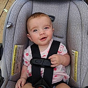 Gage is registered to the contest to win money with this photo: baby, bottle, car_seat, child, cute, face, happy, harness, holding, indoor, infant, patterned_fabric, pink_shirt, portrait, safety, seatbelt, sitting, smiling, wooden_floor, young_child