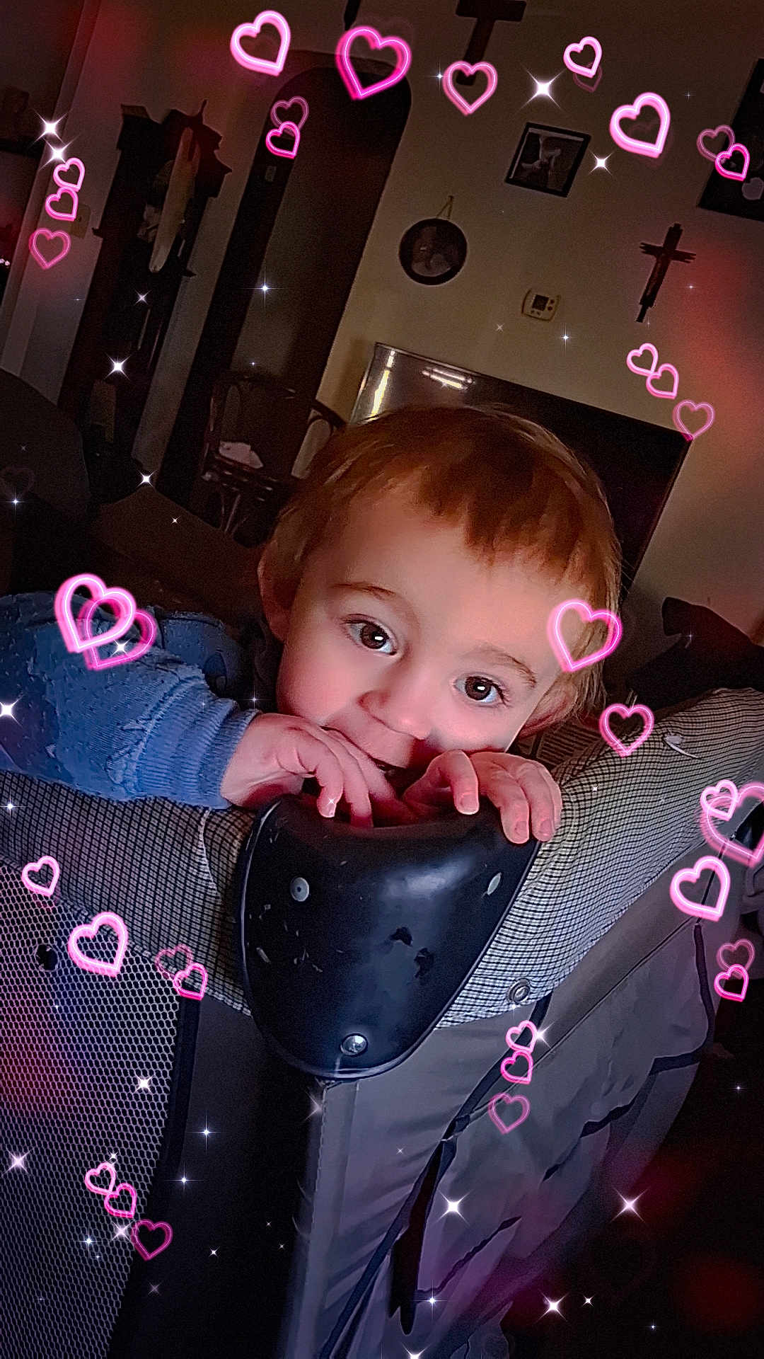 Leonidas joined the competition — help win amazing prizes! child, toddler, playpen, face, big_eyes, hands, biting, teething, blue_sweater, indoor, living_room, furniture, television, crucifix, picture_frame, hearts_overlay, sparkles, portrait, cute, playful