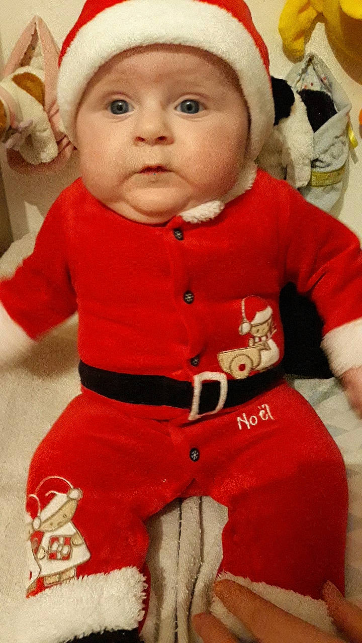 Amber participe au concours pour gagner de l'argent avec cette photo : baby, baby_products, baby_toddler_clothing, bonnet, carmine, cheek, child, christmas, christmas_eve, costume_accessory, fictional_character, headwear, human_body, long_sleeved_t_shirt, overall, person, red, sleeve, sock, toddler